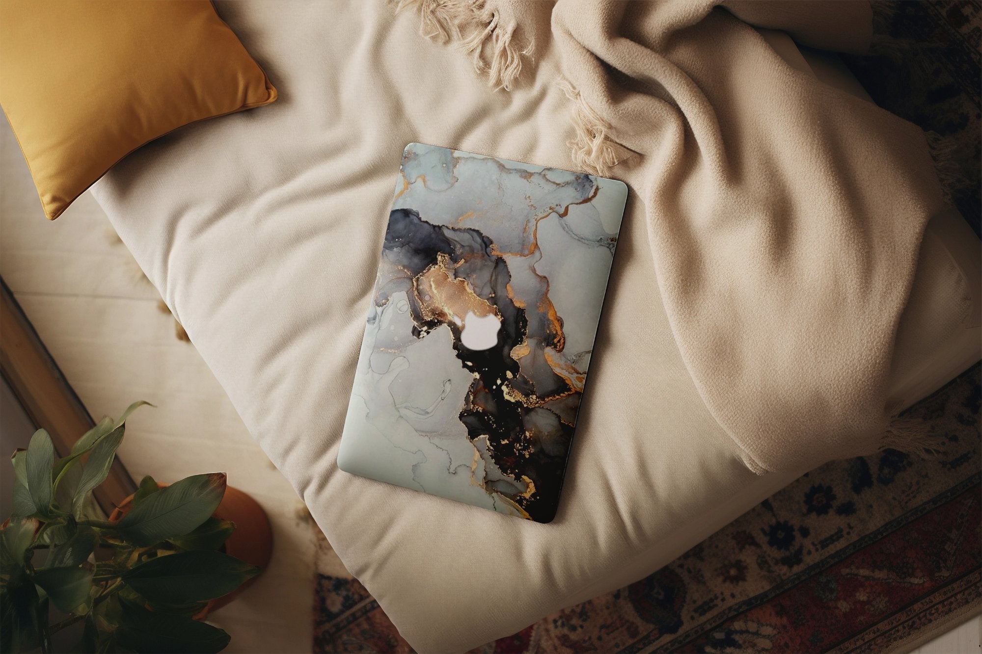 Stylish designer laptop case with marble and gold pattern on bed