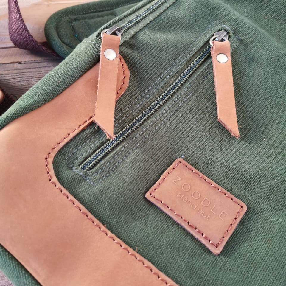 Close-up of Zoodle Olive Sling Bag's leather zipper pulls and embossed logo, showcasing premium craftsmanship and South African design.