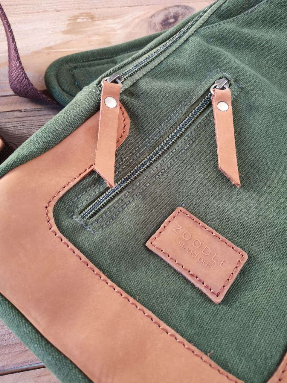 Close-up of Zoodle Olive Sling Bag's leather zipper pulls and embossed logo, showcasing premium craftsmanship and South African design.