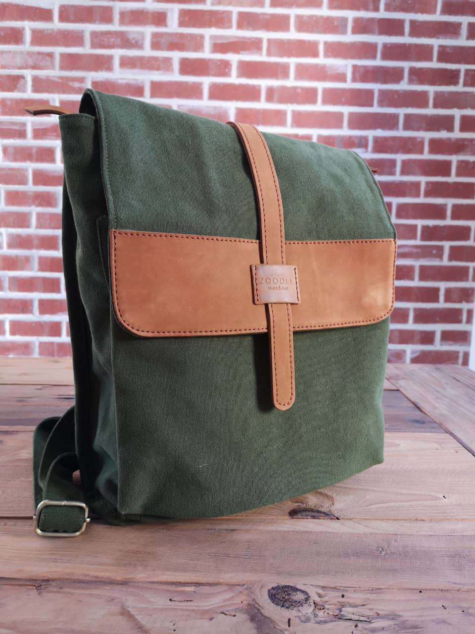Front angled view of Zoodle Laptop Backpack in green canvas and tan leather, perfect for urban travel and laptop storage.