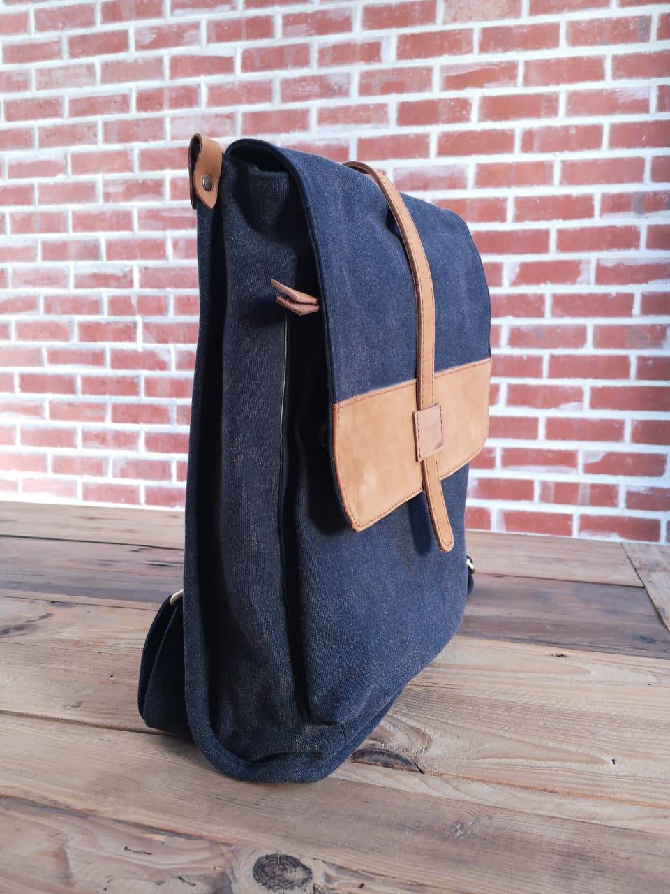 Side view of navy Zoodle Laptop Backpack with tan leather flap, combining minimalist design with practical laptop storage.