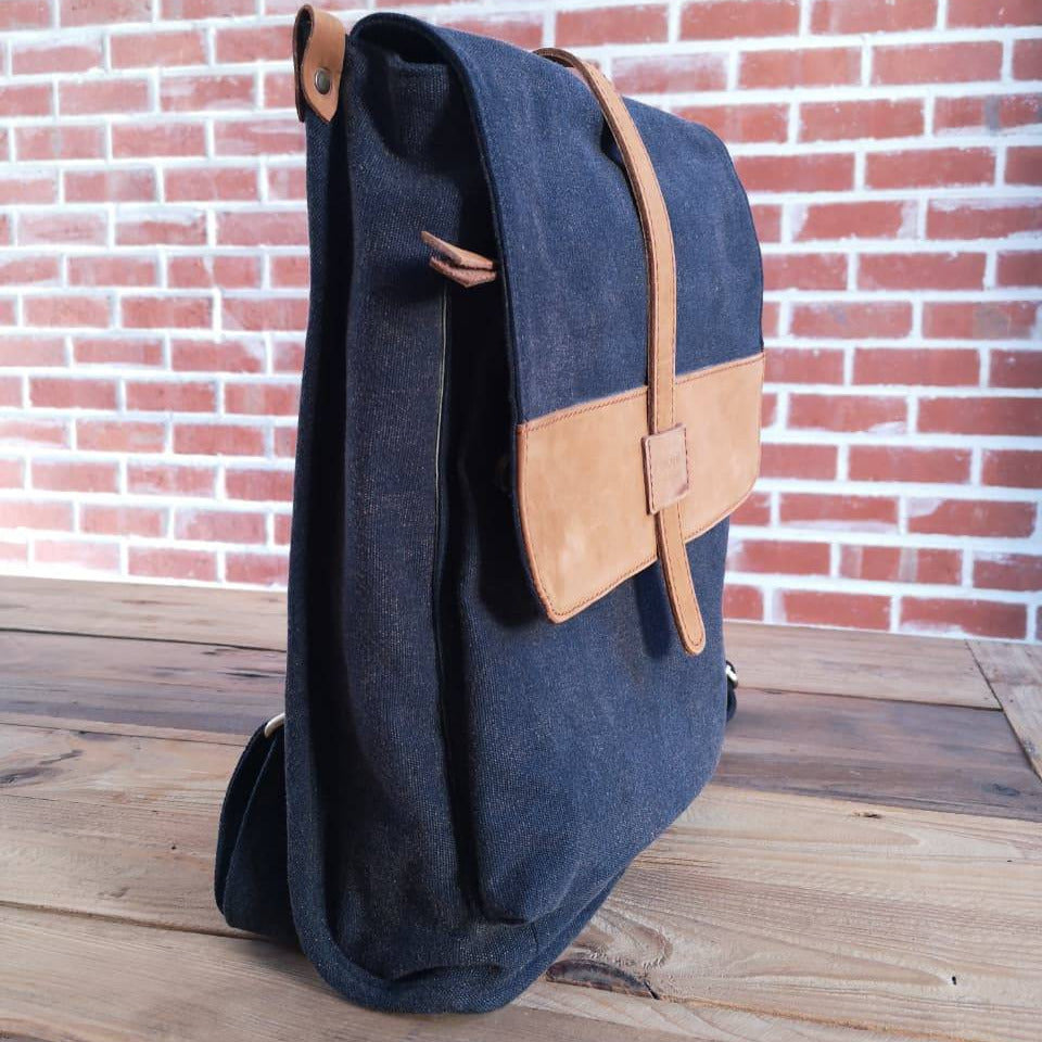 Side view of navy Zoodle Laptop Backpack with tan leather flap, combining minimalist design with practical laptop storage.