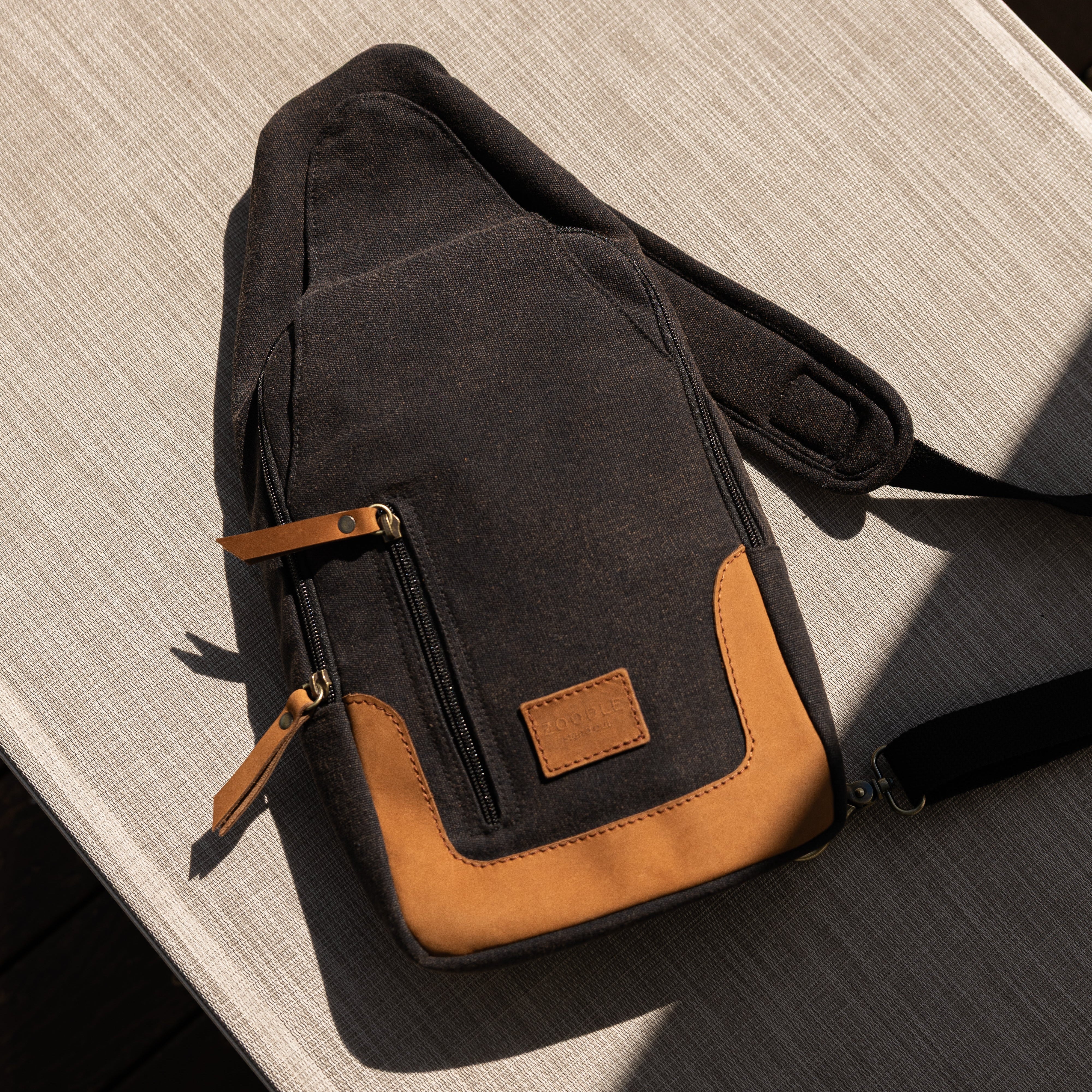 Black and brown crossbody bag on a wooden surface
