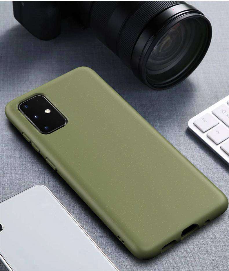Olive green Eco-Friendly Slimline iPhone Case with speckled texture, placed near camera and keyboard, ideal for eco-conscious tech users.