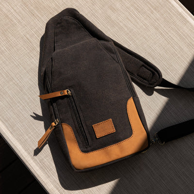 Black and brown crossbody bag on a wooden surface