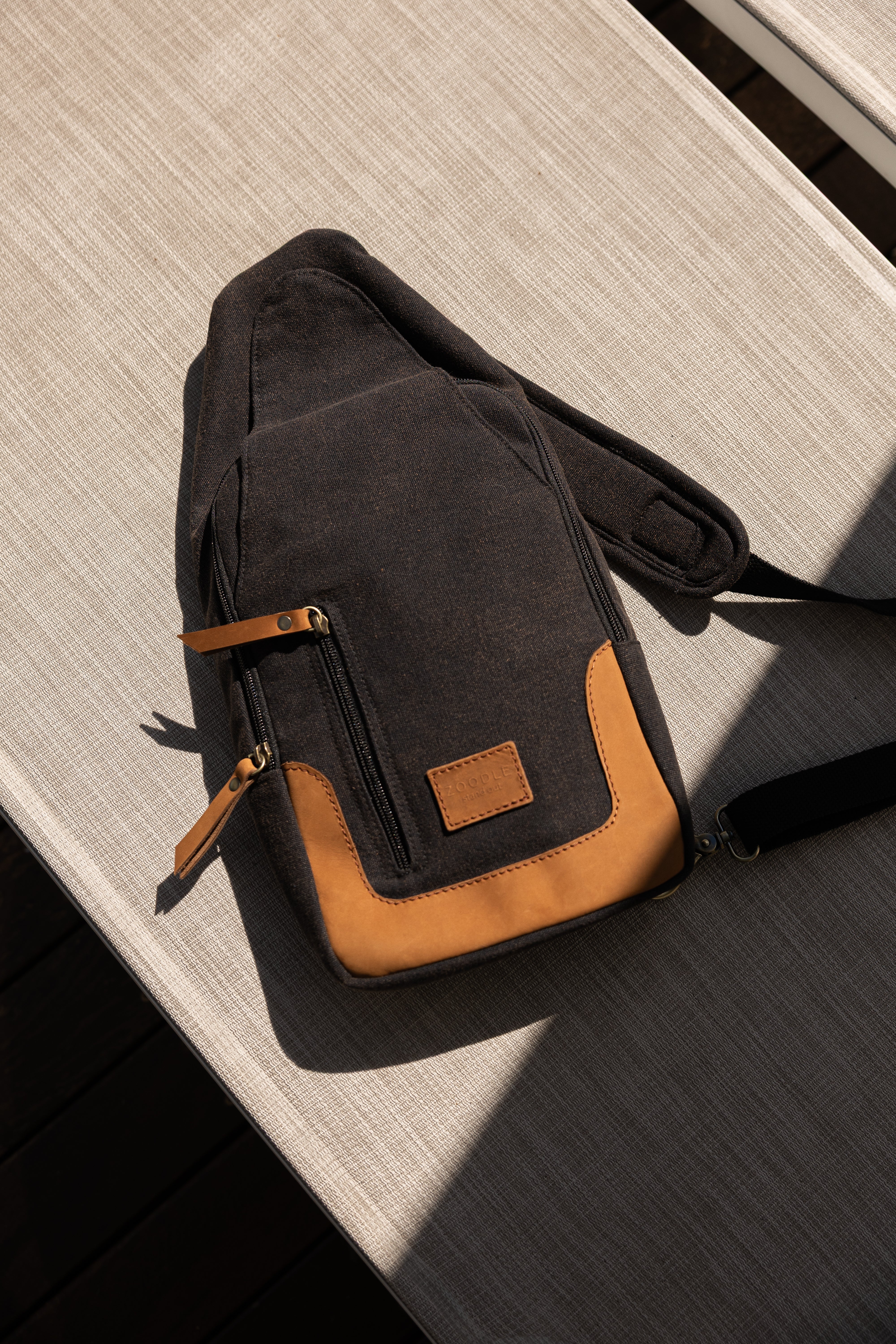 Black and brown crossbody bag on a wooden surface