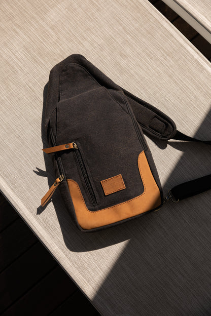 Black and brown crossbody bag on a wooden surface